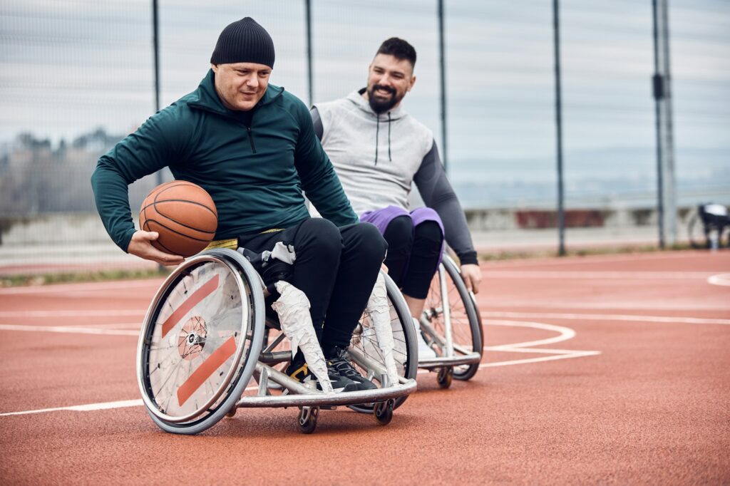 Disabled men playing wheelchair basketball outdoors.